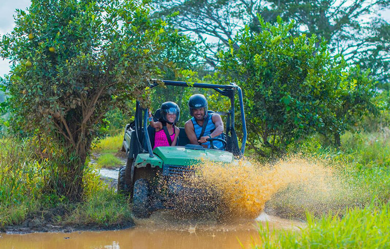 couple on all terrain vehicle driving through mud