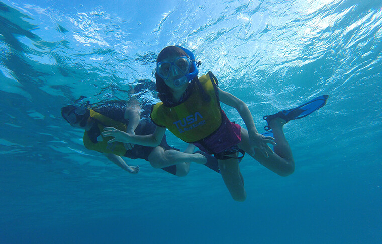 2 snorkelers looking at the camera underwater